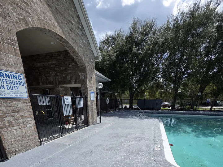 Refilled community swimming pool beside a continuous finished gray deck after surface restoration.