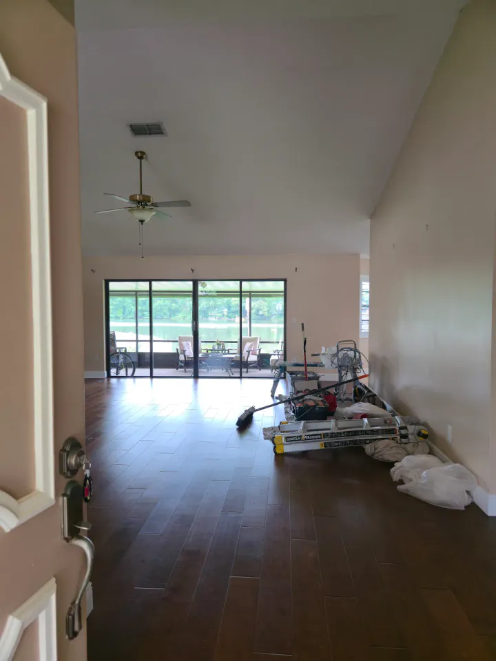 Living area with older neutral wall finish and dark wood flooring before documented repair work.