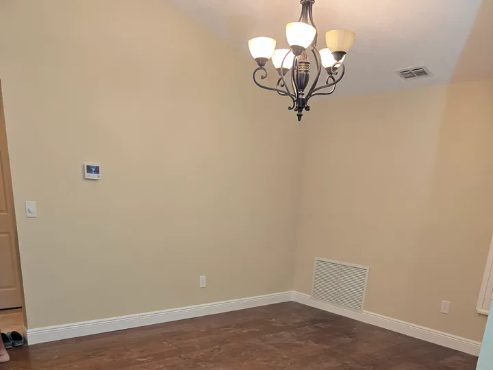 Dining area with neutral walls, white trim, dusty dark flooring, and an unfinished foreground threshold.
