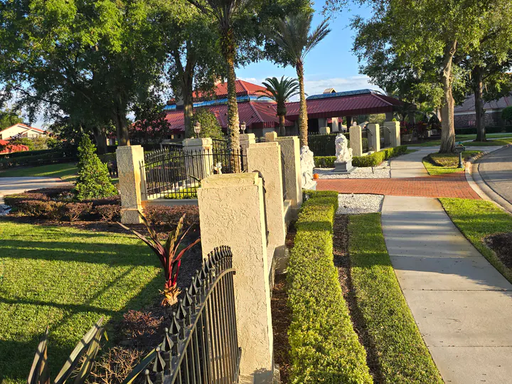 Wide view of light-colored textured entry walls and columns with black metal fencing