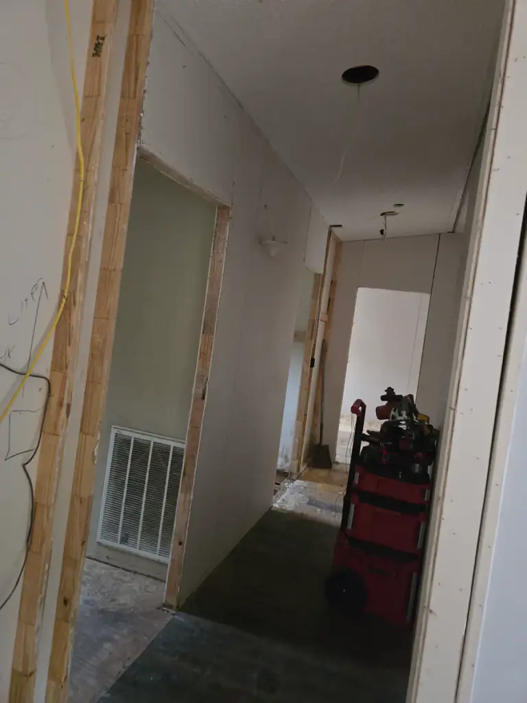 Hallway under renovation with framed openings and work tools visible