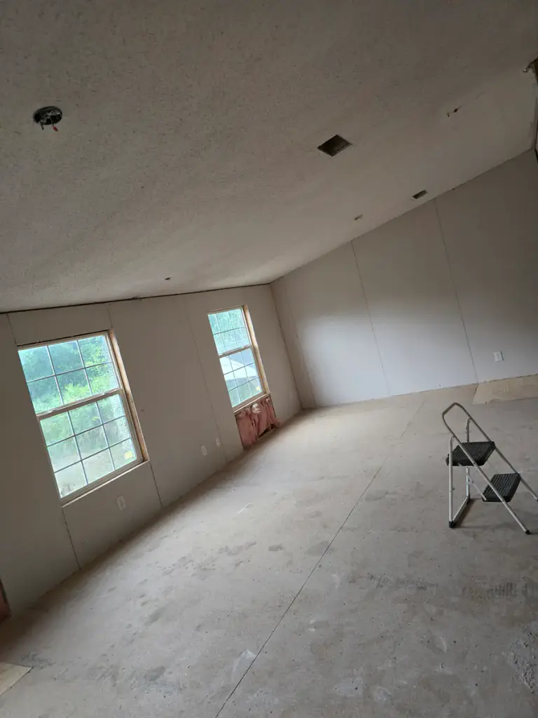 Interior room under renovation with drywall and exposed framing visible