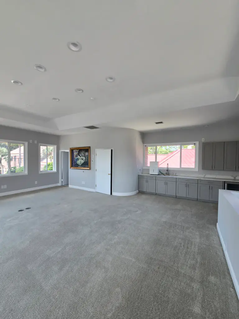 Open interior room with gray walls, a white ceiling and trim, and gray cabinetry