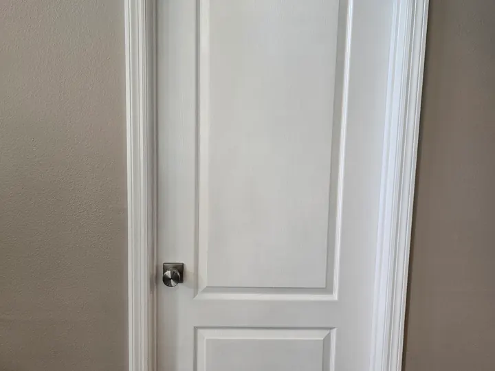Finished white paneled interior door and casing against warm neutral walls