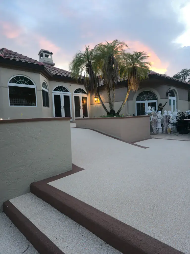 Light-tan pool-deck coating in progress around dark accent borders and steps.
