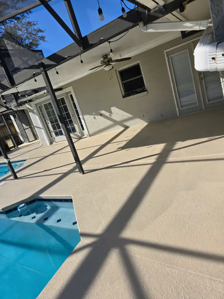 Completed light neutral coating across the patio side of a screened pool deck.