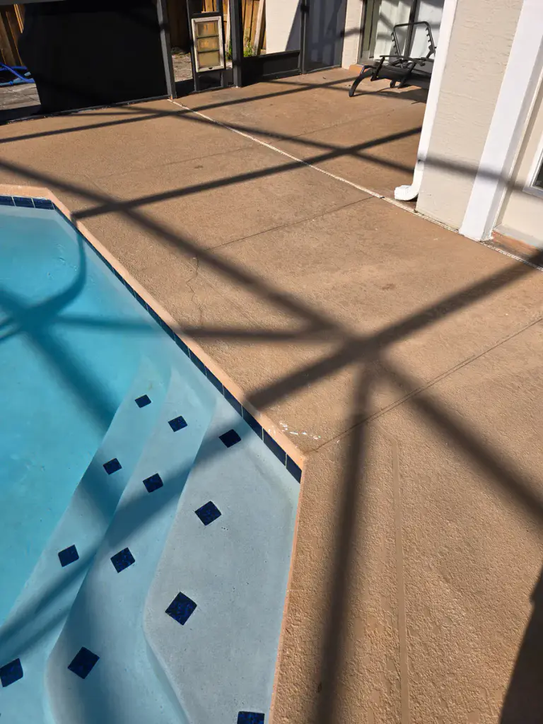Finished pool-deck coating beside the pool steps and waterline tile.