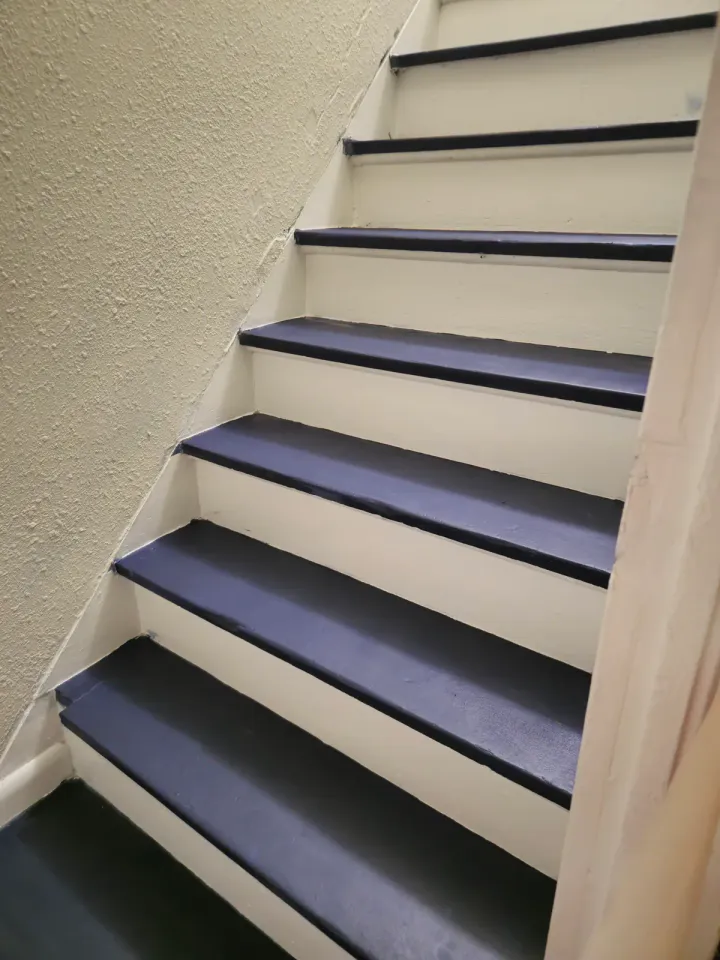 Close view of dark stair treads with contrasting light risers and walls.