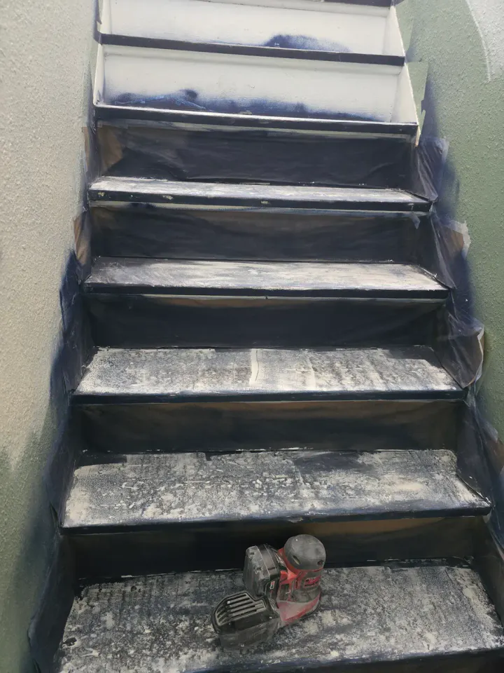 Dark stair treads covered with sanding residue during active preparation.
